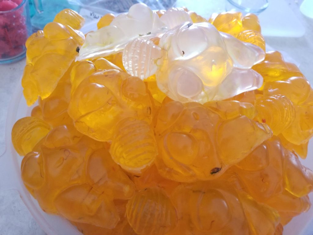 A photo of golden and white translucent Venus of Willendorf soaps with light shining through them.